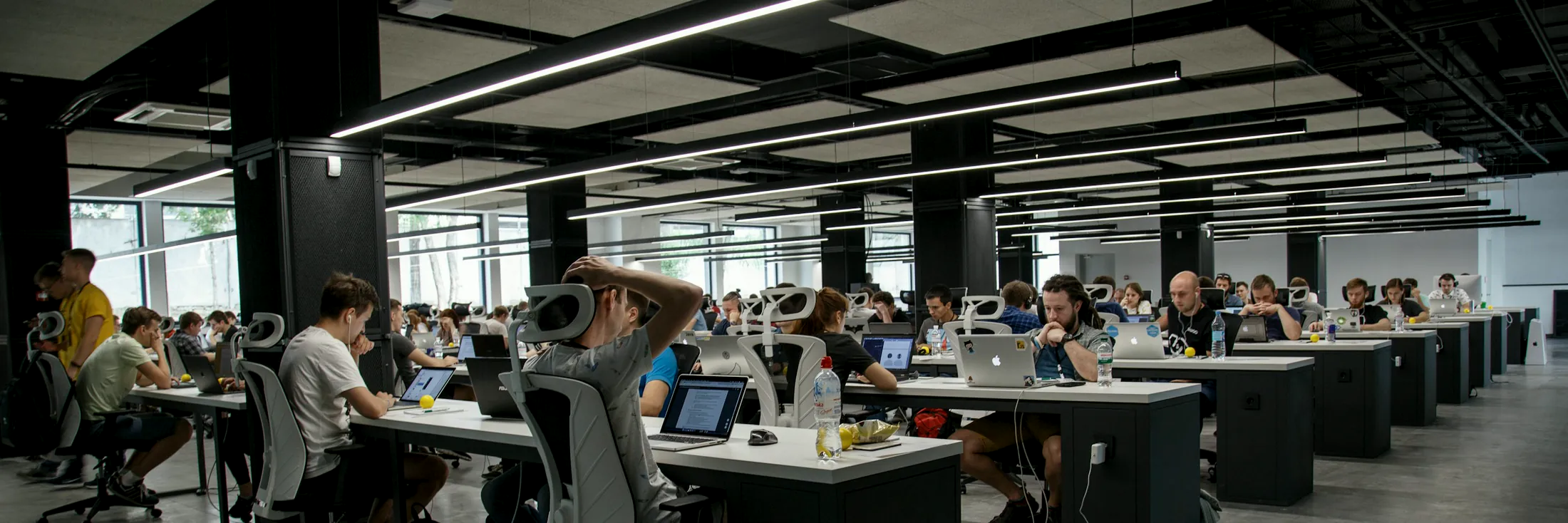 Long rows of engineers working at desks across an open technology delivery floor