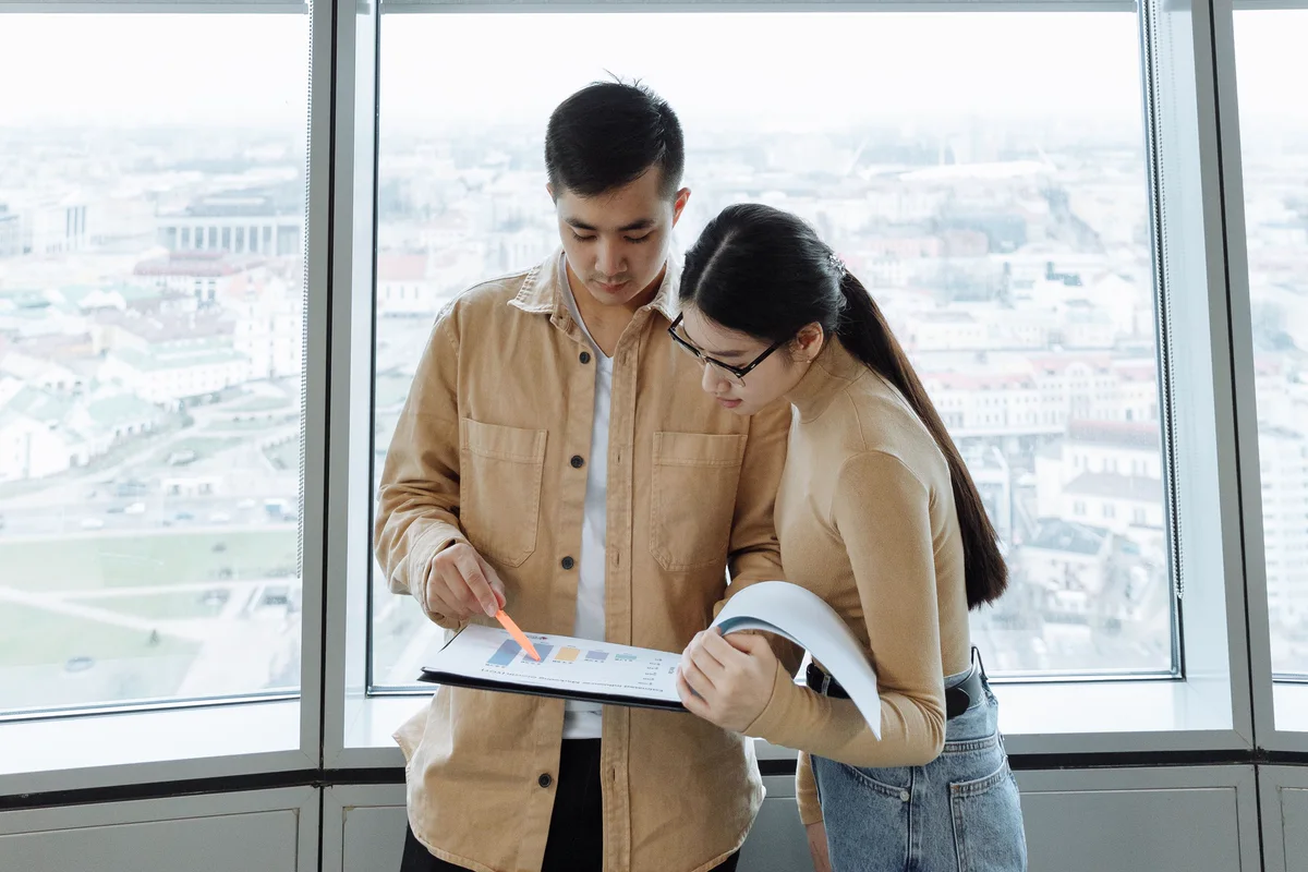 Two colleagues reviewing a document together at an office window